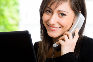 A female is holding a phone up to her ear and smiling